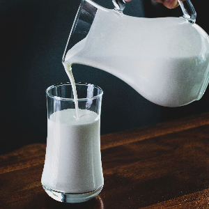 a glass pitcher of milk pouring into a drinking glass