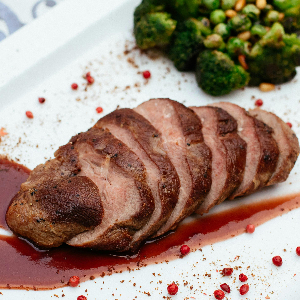 a sliced duck breast covered in a red sauce